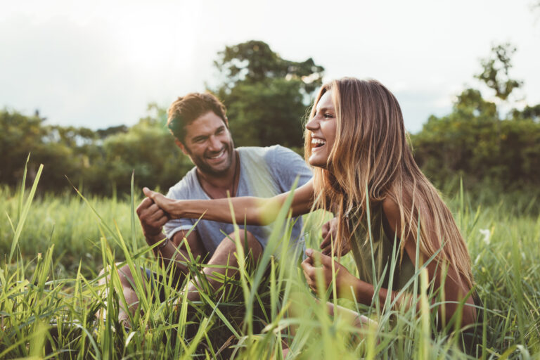 couple smiling and holding hands in the grass