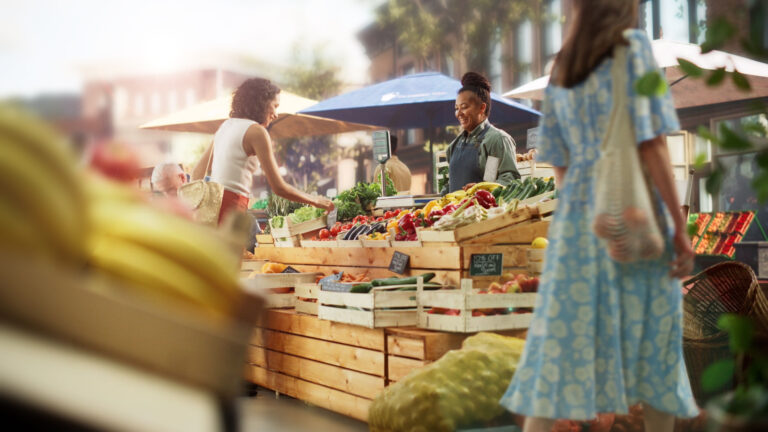 woman choosing fruits and vegetables from a vendor at the farmers market