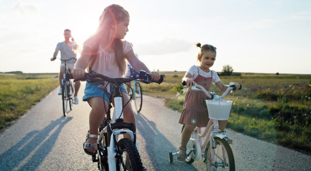 girls riding bicycles on a trail followed by their dad, enjoying the East Orlando allure