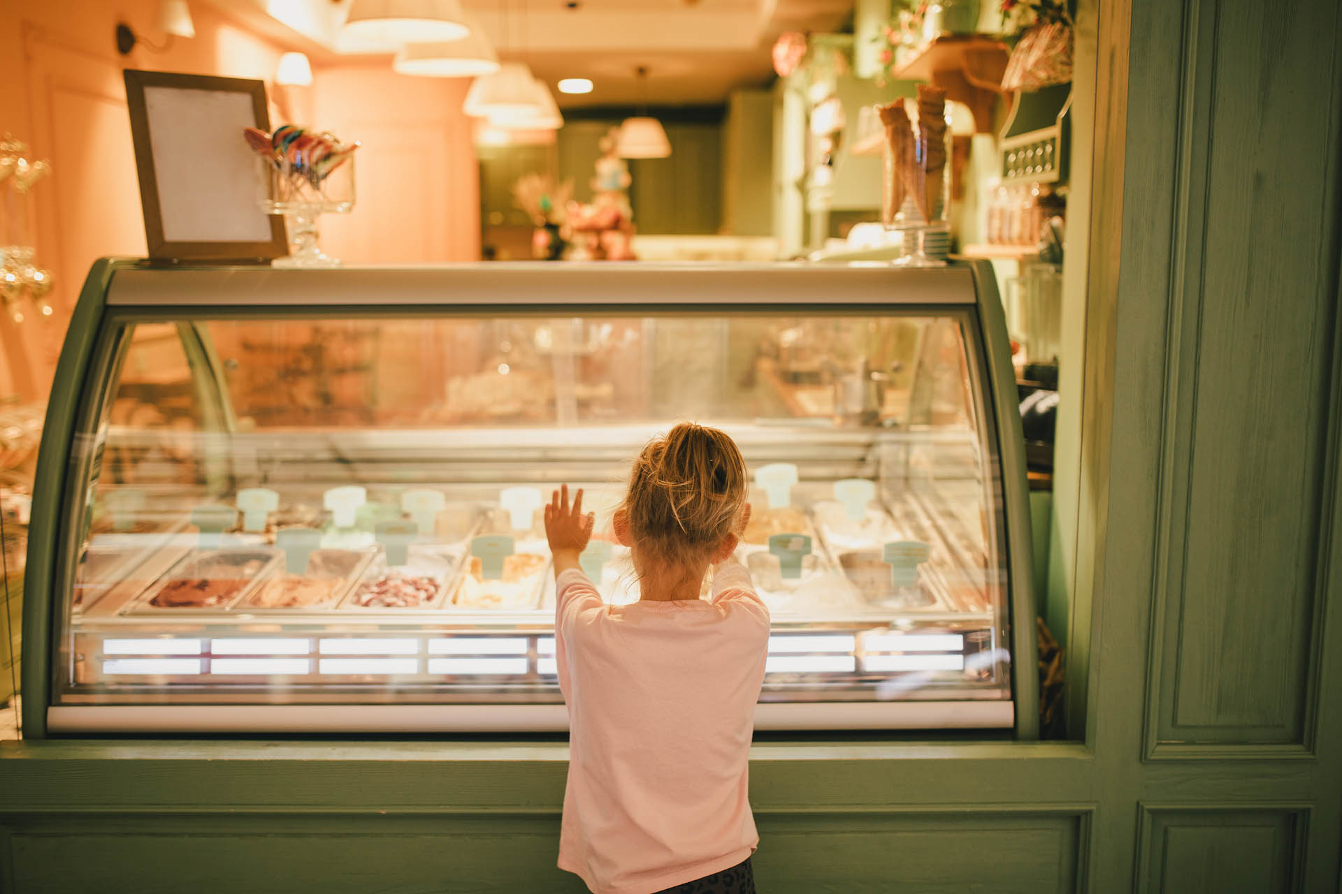 Cute little girl standing near ice-cream shop, choosing ice-cream - Unique Ideas for Spring Break in Orlando