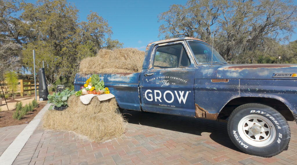 Classic blue pickup truck next to a hay bale with produce
