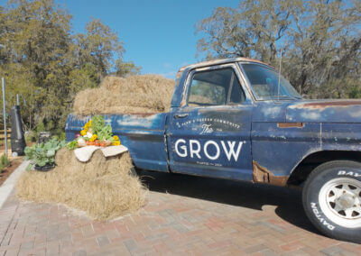 Classic blue pickup truck next to a hay bale with produce